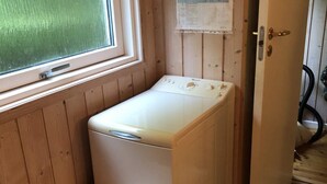 A compact laundry room with a washing machine and a small stool. - 4 Star Holiday Home in Vejby (Vejby)