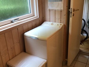 A compact laundry room with a washing machine and a small stool. - 4 Star Holiday Home in Vejby (Vejby)