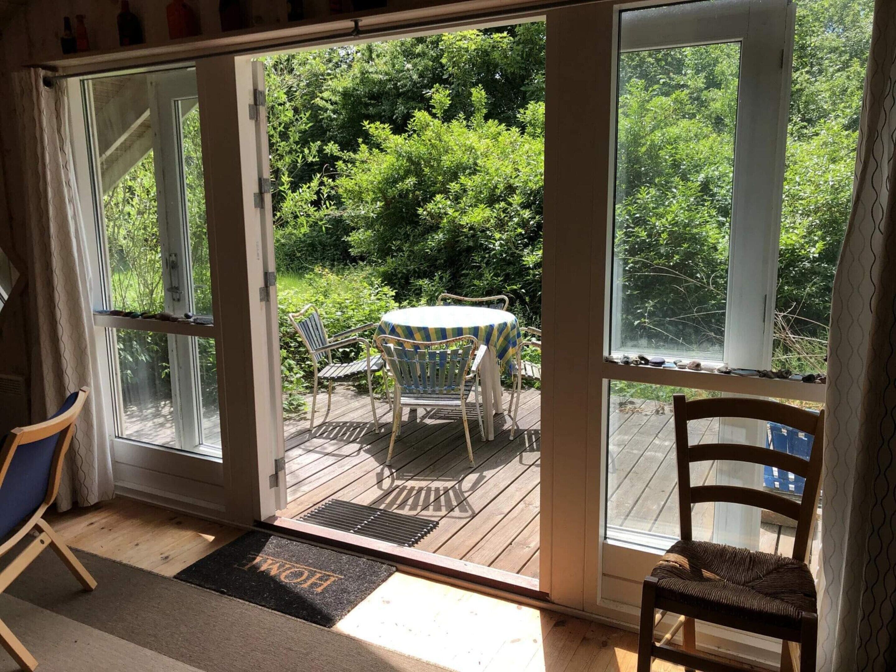 Ein Zimmer mit einer Schiebetür und Zugang zu einer Terrasse, auf der Tisch und Stühle stehen.