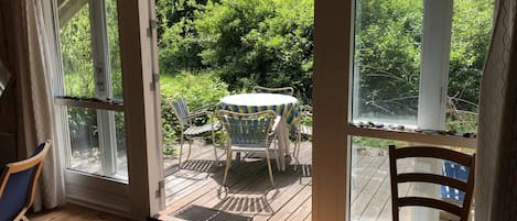 A room with a sliding glass door leading to an outdoor deck with a table and chairs.