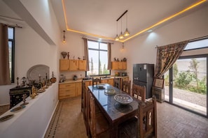 A spacious kitchen with wooden cabinets, a dining table, and a refrigerator. - Lovely Villa 4 Bedrooms and Swimming pool (Ghazoua)