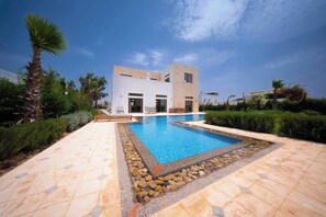 A modern two-story house with a swimming pool, surrounded by landscaped greenery and a clear sky. - Lovely Villa 4 Bedrooms and Swimming pool (Ghazoua)
