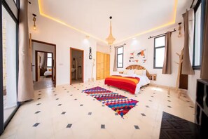 Ein geräumiges Schlafzimmer mit einem großen Bett, einem farbenfrohen Teppich und einer modernen Kronleuchter.