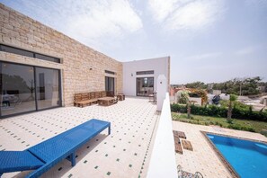 A modern outdoor patio with a pool, wooden furniture, and a clear view of the surrounding area. - Lovely Villa 4 Bedrooms and Swimming pool (Ghazoua)