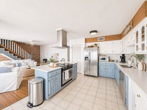 A modern kitchen with a central island, stainless steel appliances, and light blue cabinetry. - False River Waterfront Escape in Charming New Roads (New Roads)