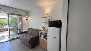 Eine moderne Küche mit grauem Sofa, einer Mikrowelle und einem Kühlschrank.