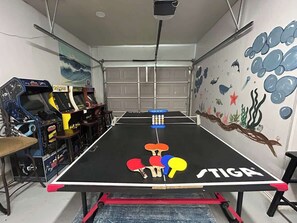 A ping pong table with a 'STIGA' logo, surrounded by arcade machines and a mural of underwater scenes. - Hot tub, Game room, Pool, 7 miles to stockyards (Haltom City)