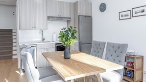 A modern kitchen with a built-in oven, a refrigerator, and a dining area with a wooden table and grey upholstered chairs. -  Bright, Cozy, Separate Entrance, Guest Room, Walk.: Subway, Shop, restaurants.. (Toronto)