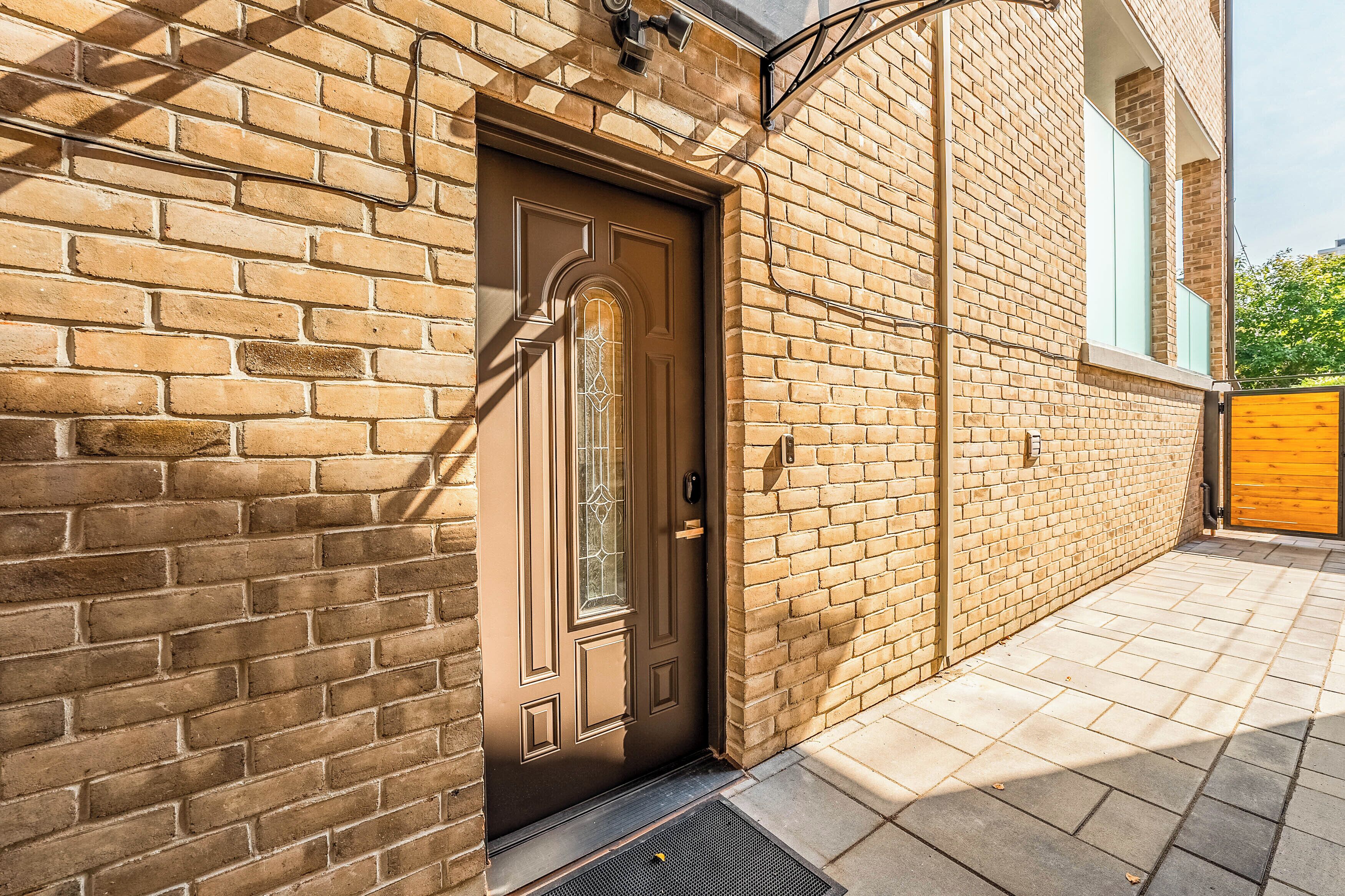 A brick building with a brown door, a window with a decorative glass design, and a yellow gate.