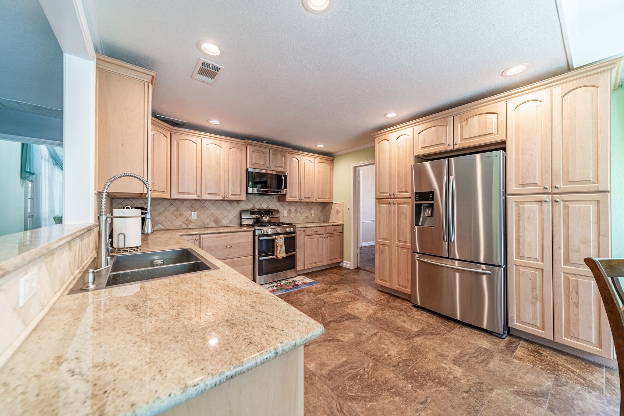 A modern kitchen with wooden cabinets, stainless steel appliances, and a granite countertop.
