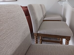 A section of a room with a beige upholstered sofa and a wooden chair with a cushioned seat. - Aggieland Villa - Themed 4-Bedroom Suite Townhome - Mins to Texas A&M University (College Station)