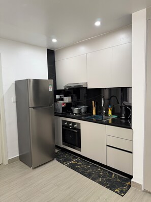 Uma cozinha moderna com eletrodomésticos de aço inoxidável, painel de parede de mármore preto e armários em tons claros.