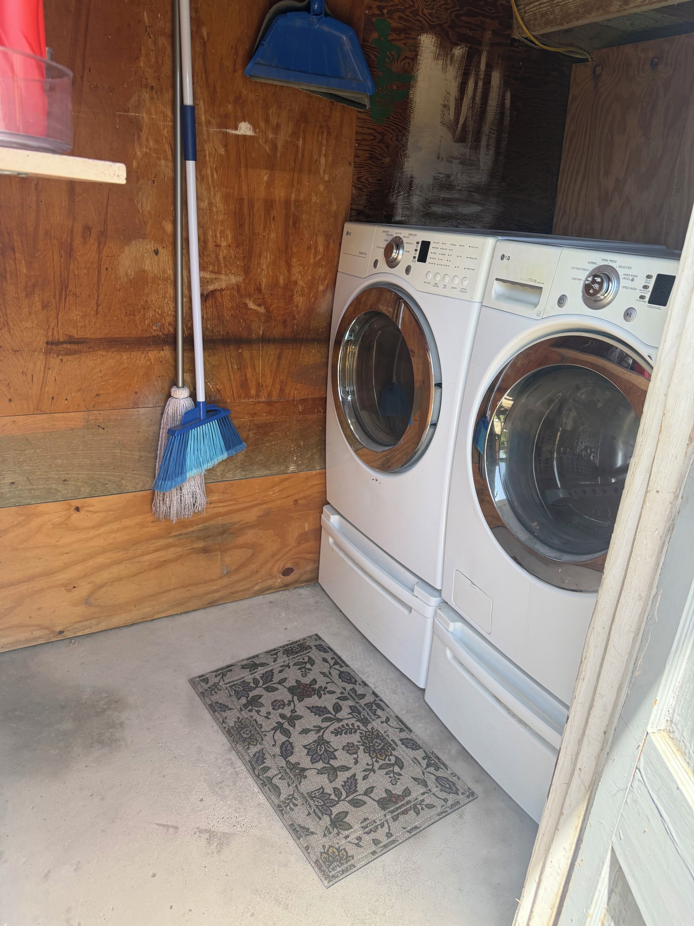 Une buanderie équipée d’un lave-linge et d’un sèche-linge, d’un balai et d’un tapis.