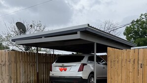 A covered parking area with a white SUV parked inside. - Stay Close to Everything  15 Min to Laughlin AFB (Del Rio)