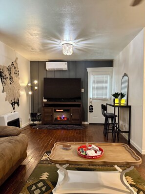 A living room with a flat-screen TV, a fireplace, a dining area with a table and chairs, and a sofa. - Stay Close to Everything  15 Min to Laughlin AFB (Del Rio)