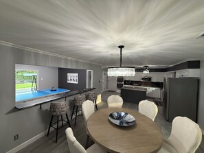 A modern kitchen with a central island, bar seating, and a dining area with a round table. - Lakefront with amazing views on beautiful Lake Hamilton in Hot Springs, Arkansas (Hot Springs)
