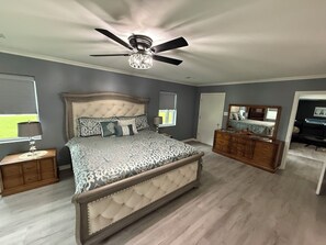 A bedroom with a tufted headboard, a large bed, a dresser, a ceiling fan, and a window with a view. - Lakefront with amazing views on beautiful Lake Hamilton in Hot Springs, Arkansas (Hot Springs)