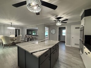 A modern kitchen with a central island, a dining area with chairs, and a ceiling fan. - Lakefront with amazing views on beautiful Lake Hamilton in Hot Springs, Arkansas (Hot Springs)