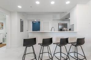 Eine moderne Küche mit einer zentralen Kochinsel, Barhocker und einer blauen Tür.