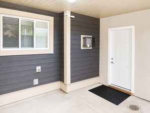 A house exterior with a dark siding, a white door, and a small window with blinds. - Cozy 2-bedroom suite near Mundy Park & Austin Heights (Coquitlam)