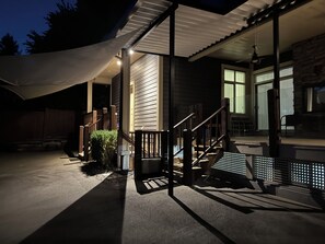 A covered outdoor area with a staircase leading to a porch, a white canopy, and a stone building in the background. - Cozy 2-bedroom suite near Mundy Park & Austin Heights (Coquitlam)