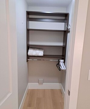Ein begehbarer Kleiderschrank mit Holzboden, einer Kleiderstange und einem Regalsystem.