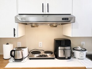 Eine moderne Küche mit Edelstahlgeräten, darunter eine Kaffeemaschine, ein Wasserkocher, ein Slow-Cooker und ein Toaster.