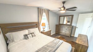 A bedroom with a bed, a dresser, a mirror, a ceiling fan, and a door. - Brittleville Bunkhouse: Peaceful Country Getaway (Brooksville)