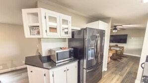 A compact kitchen with a refrigerator, microwave, and white cabinetry. - Brittleville Bunkhouse: Peaceful Country Getaway (Brooksville)