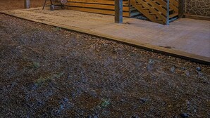 A covered outdoor area with a wooden staircase leading up to a building, surrounded by a gravel path. - Brittleville Bunkhouse: Peaceful Country Getaway (Brooksville)