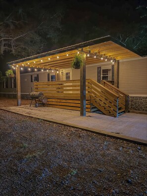 A covered outdoor area with a wooden staircase leading up to a building, surrounded by a gravel path.