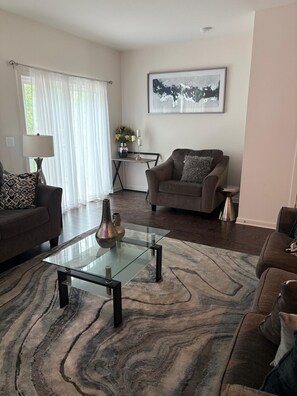 A living room with a glass coffee table, two sofas, a rug, and a painting on the wall. - 3-bedroom, 2.5 bath cozy new townhouse in tranquil Stafford with AC and comfort (Stafford)