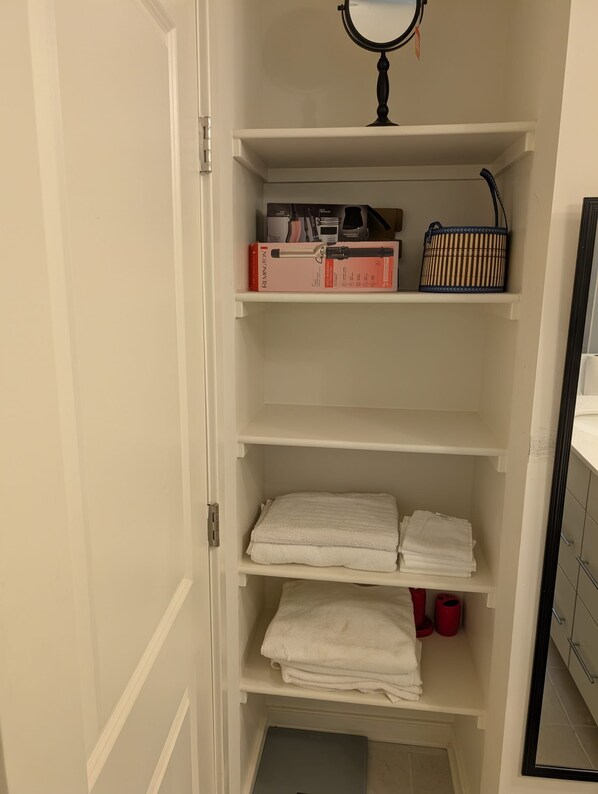 A closet with shelves containing folded towels, a mirror, and storage boxes. - 3-bedroom, 2.5 bath cozy new townhouse in tranquil Stafford with AC and comfort (Stafford)