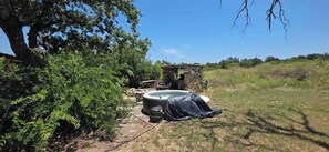 Un bain à remous extérieur, avec une structure en pierre à proximité, le tout entouré de verdure.