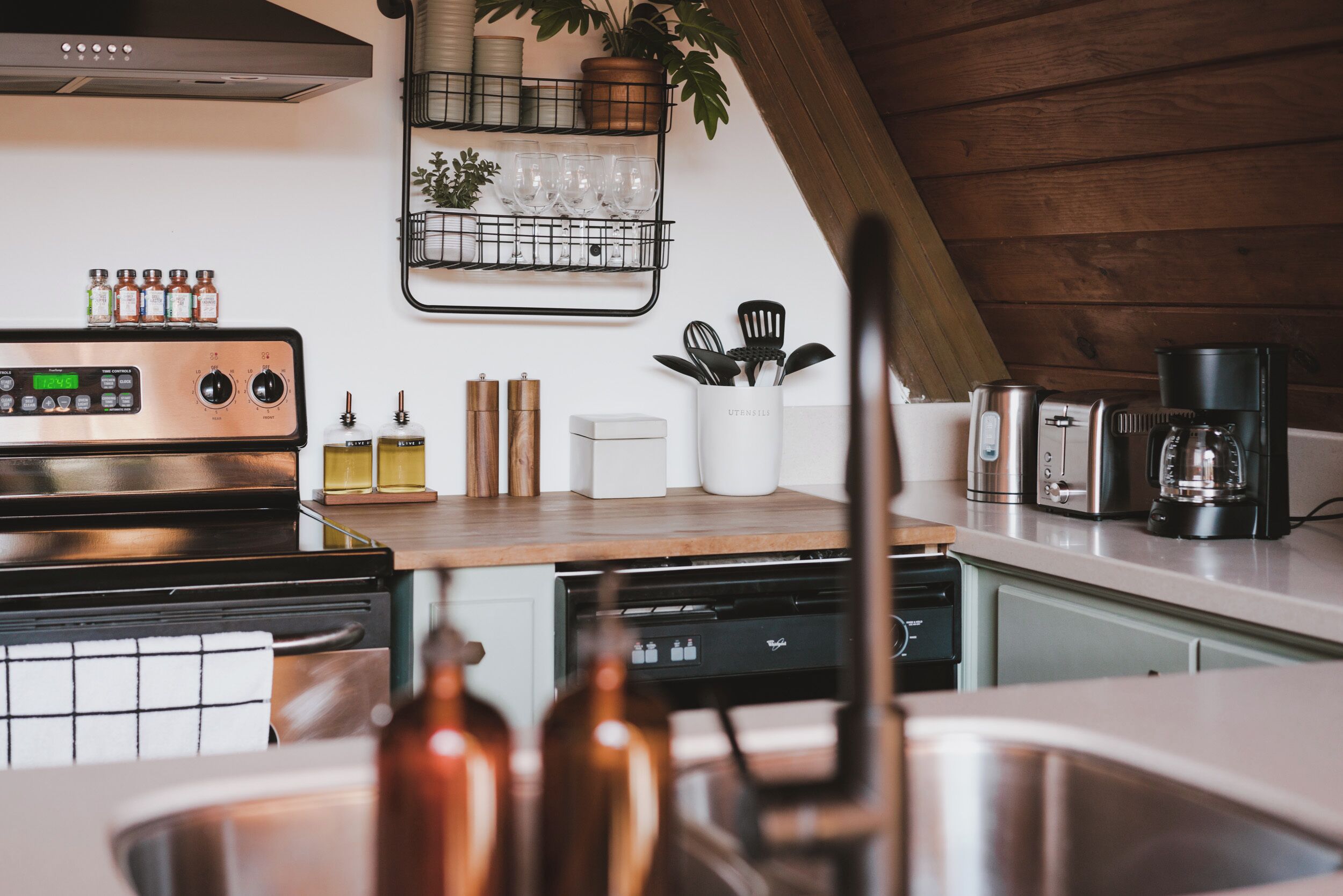 A modern kitchen with a stainless steel range, a dishwasher, and a coffee maker.