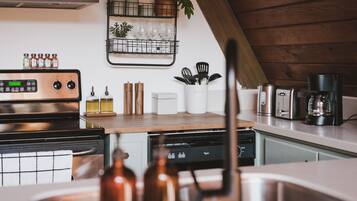 A modern kitchen with a stainless steel range, a dishwasher, and a coffee maker.