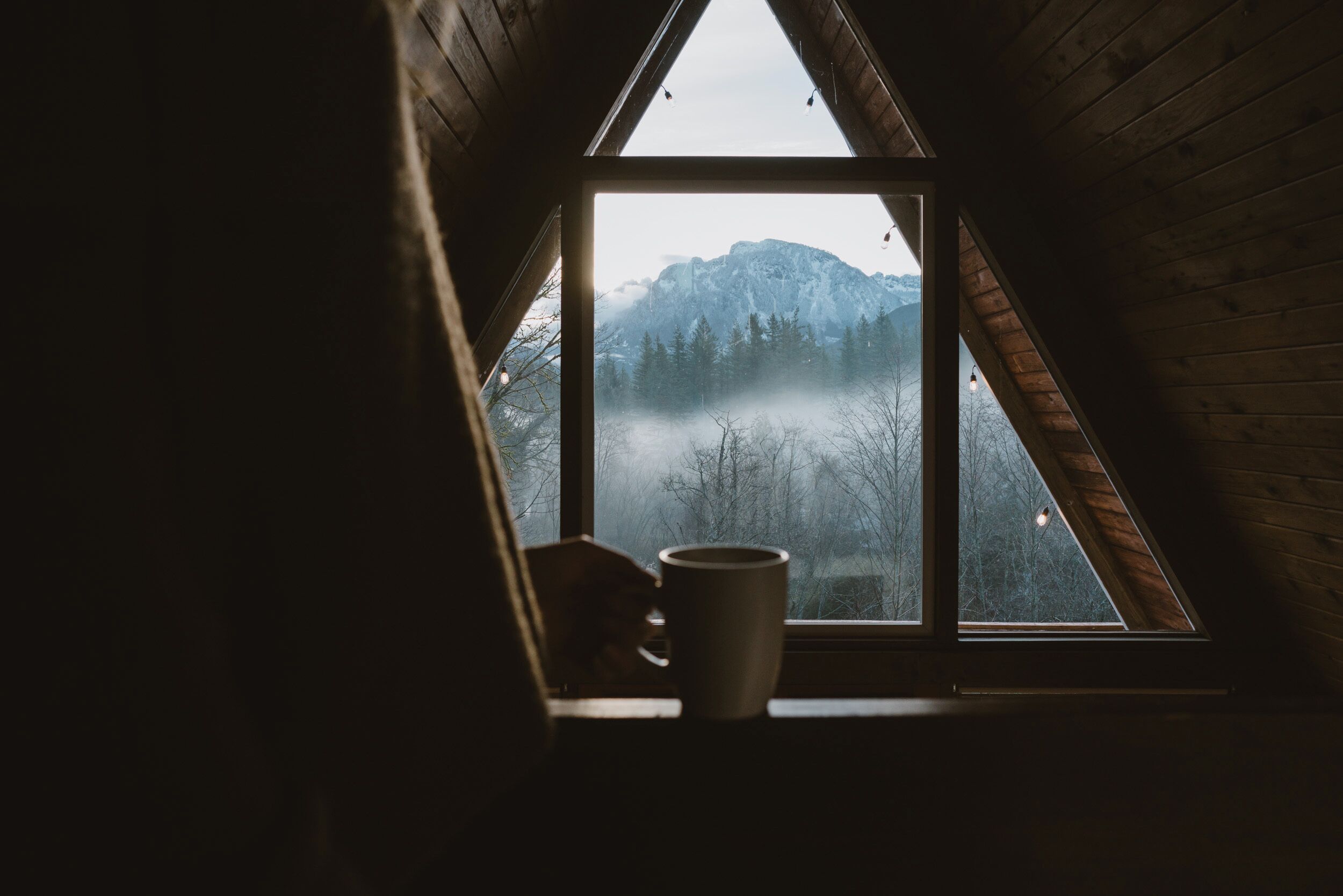 Ein Zimmer mit Fensterblick auf eine gebirgige Landschaft.