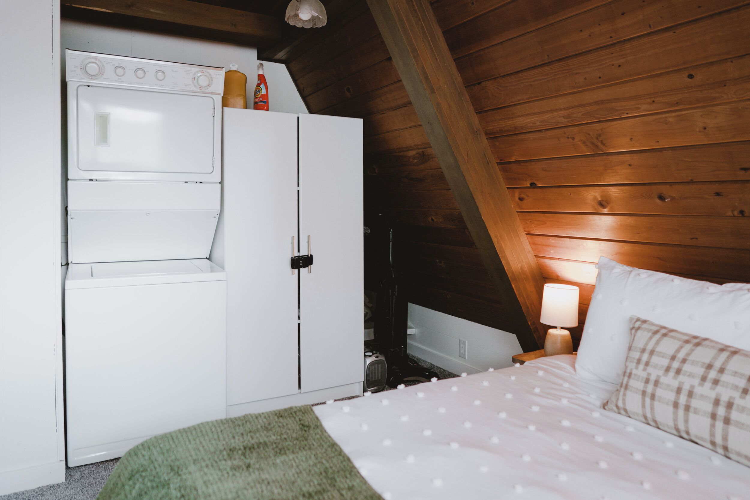 Quarto com cama, máquina de lavar e abajur.