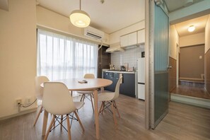 Eine moderne Küche mit Essbereich, ausgestattet mit einem runden Tisch und Stühlen, einer Klimaanlage und Blick durch eine Glastür.