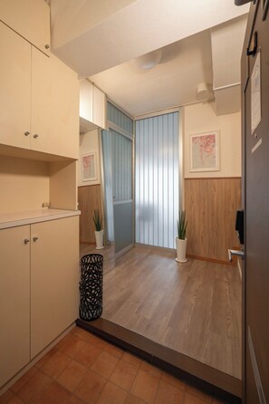 Ein Zimmer mit Holzboden, einem weißen Schrank, einer Tür mit Griff und einem Blumentopf.