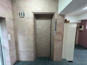 Ein Aufzug mit Hinweisschild Nummer 1, einer Tür und einem Bedienfeld an der Wand.