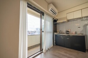 Eine moderne Küche mit Schiebeglasdoor zu einem Balkon, einem eingebauten Geschirrspüler und einer gefliesten Spritzschutzwand.