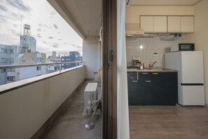 Ein Balkon mit Blick auf die Stadt, eine kleine Küche mit einer Mikrowelle und einem Kühlschrank.