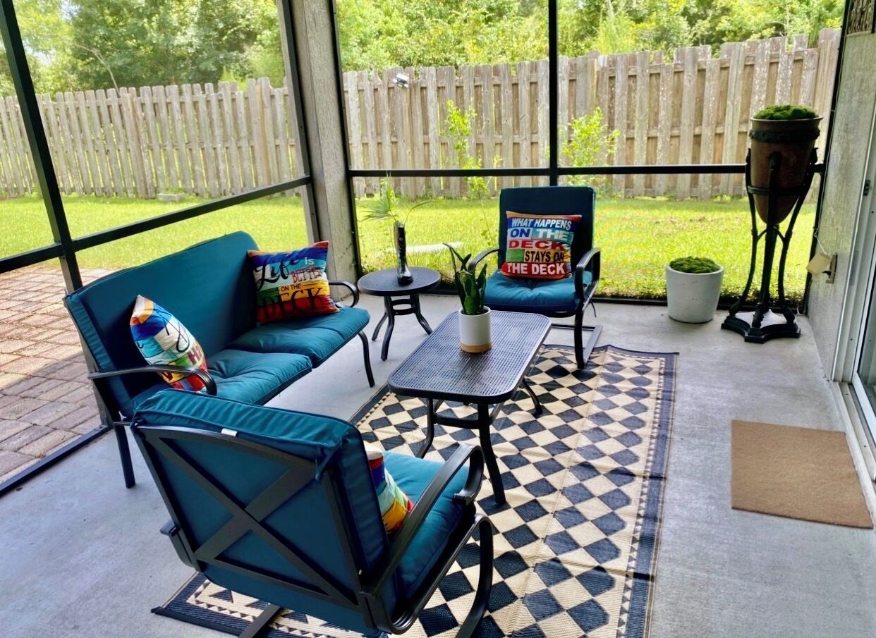 Um pátio externo com um sofá azul, uma mesa pequena e uma cadeira.