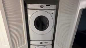 Ein kleiner Waschraum mit zwei übereinandergestapelten weißen Samsung Waschmaschinen.