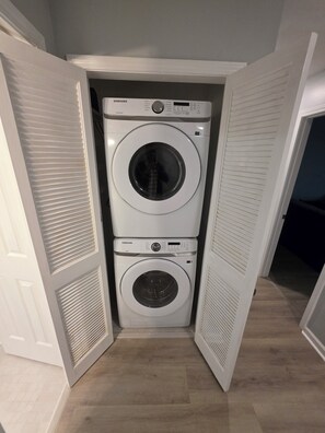 A compact laundry room with two stacked white Samsung washing machines. - Modern Comfort 3-bedroom house near Downtown Atlanta (Atlanta)
