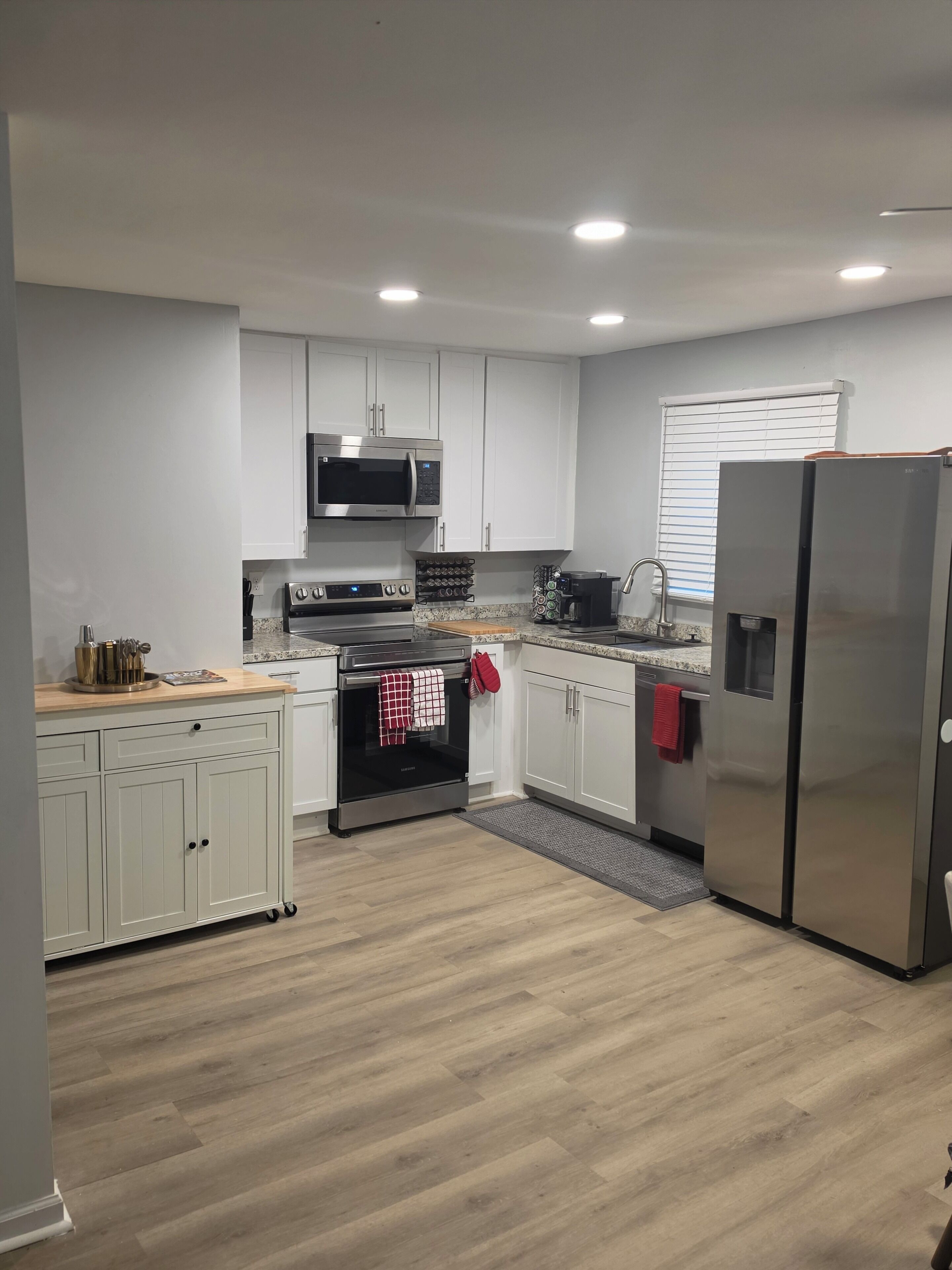 Una cocina moderna con armarios blancos, electrodomésticos de acero inoxidable y encimera de madera.