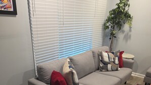 Ein modernes Wohnzimmer mit einer grauen Eckcouch, einem kleinen runden Tisch und einer Zimmerpflanze.