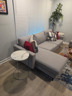 A modern living room with a grey sectional sofa, a small round table, and a potted plant. - Modern Comfort 3-bedroom house near Downtown Atlanta (Atlanta)