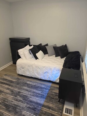 A bedroom with a bed, pillows, a rug, a dresser, and a heater. - Modern Comfort 3-bedroom house near Downtown Atlanta (Atlanta)